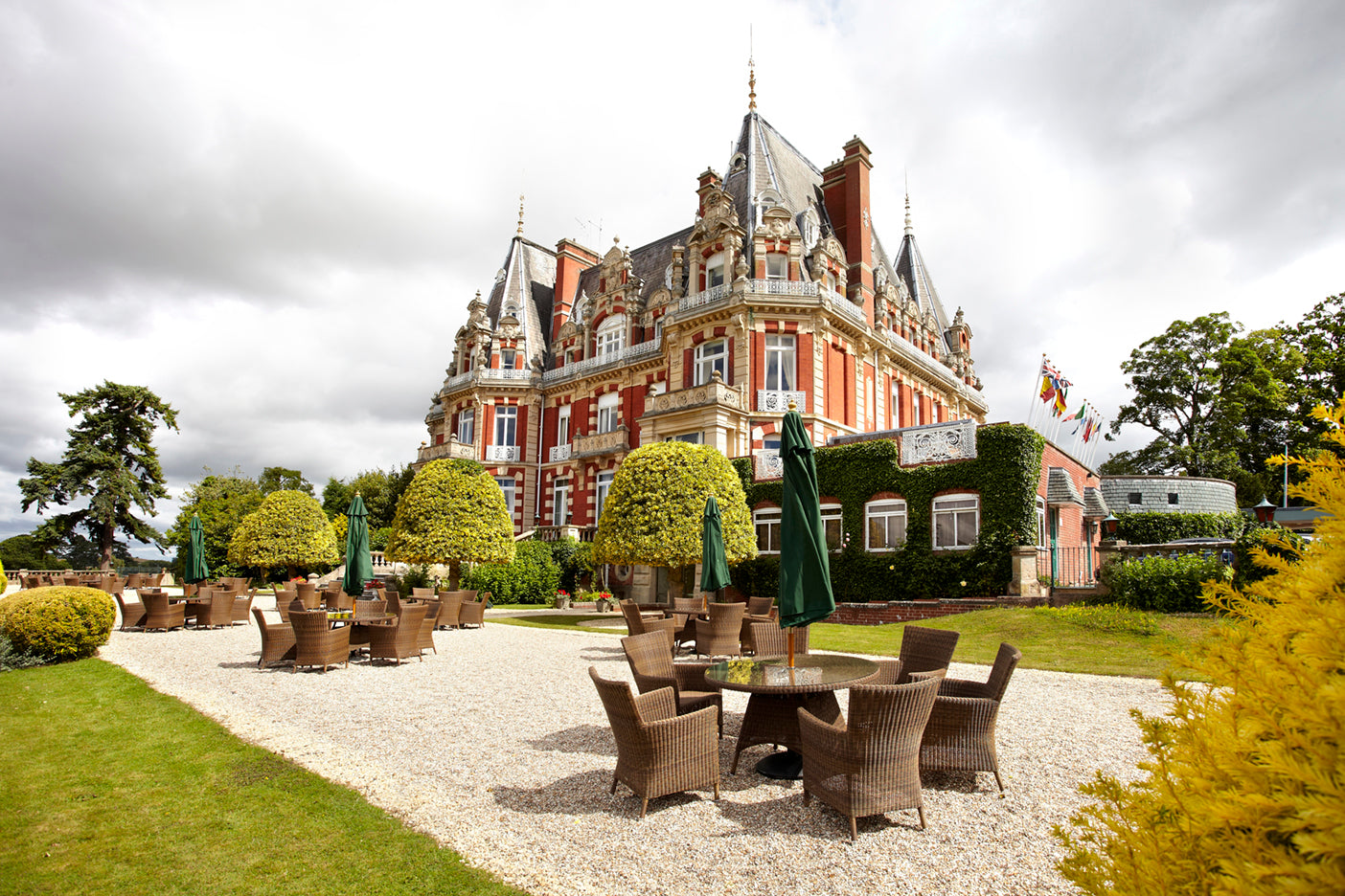 Bespoke Alexander Rose Commercial Weave chairs with green parasols and round table at Impney Chateaux
