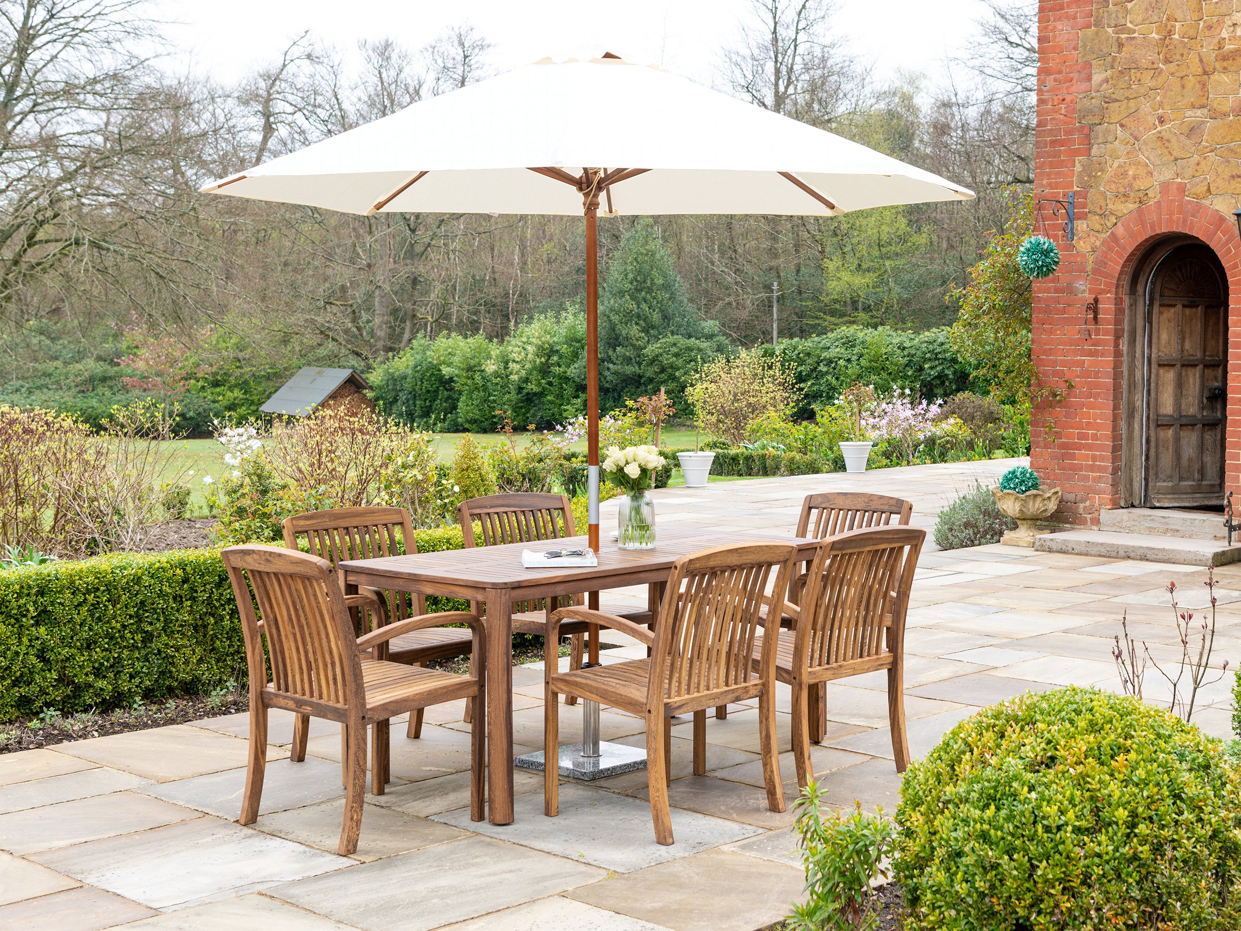 6-seater rectangular outdoor table with 6 arm chairs and a cream wooden parasol